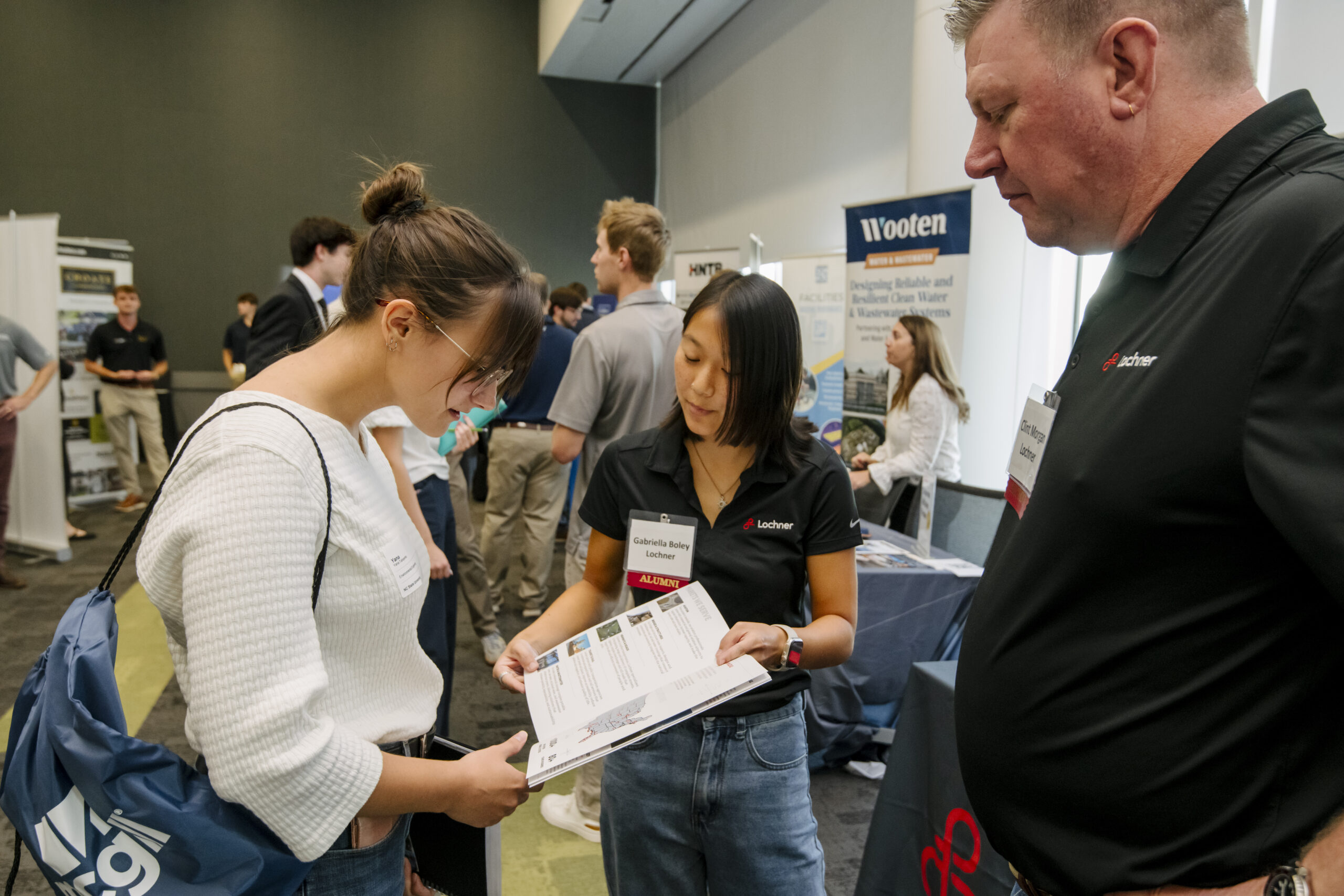A photo of people at a career fair, looking at a booklet.