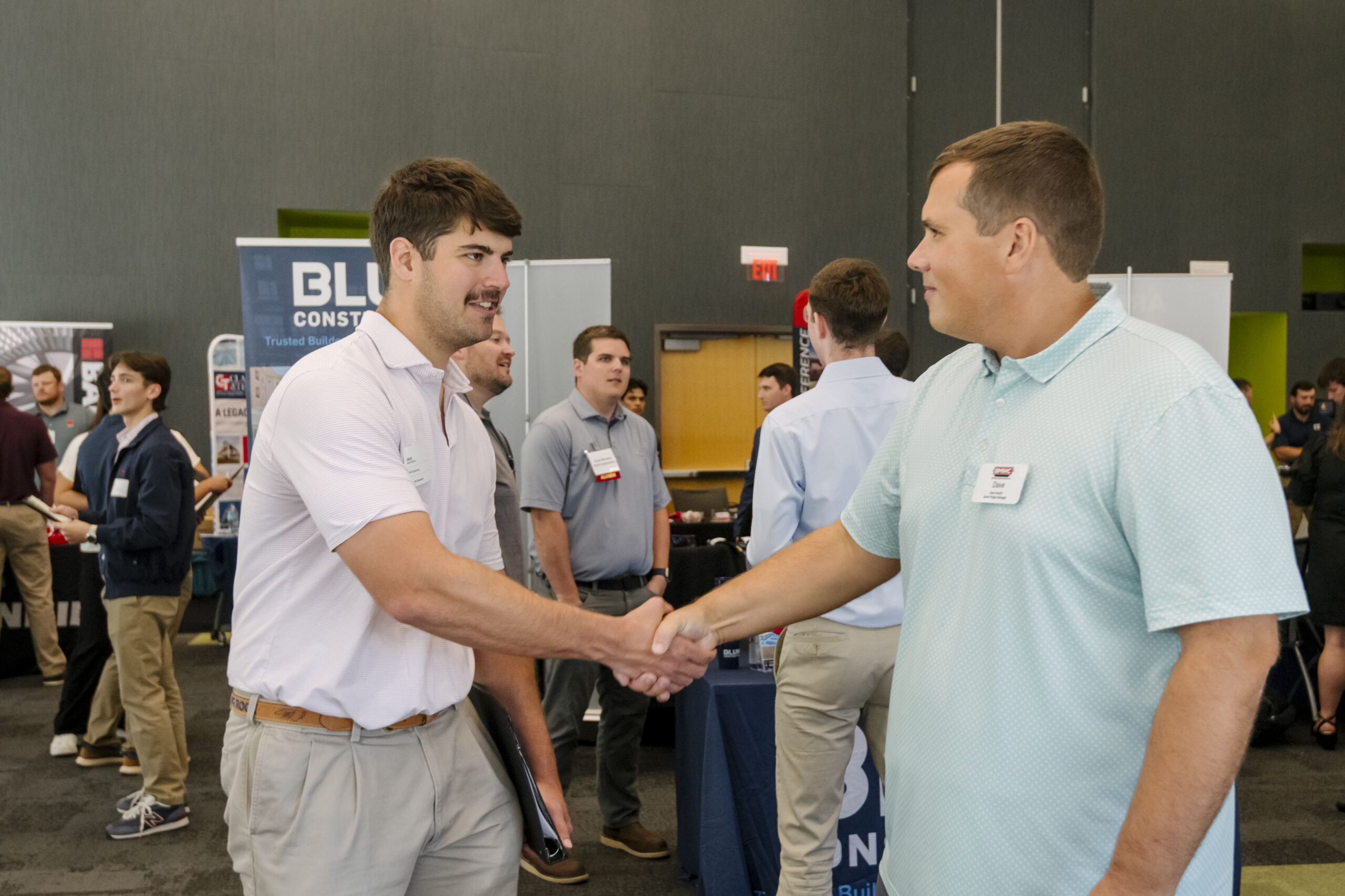 Photo shows a student and industry professional shaking hands at a career fair.