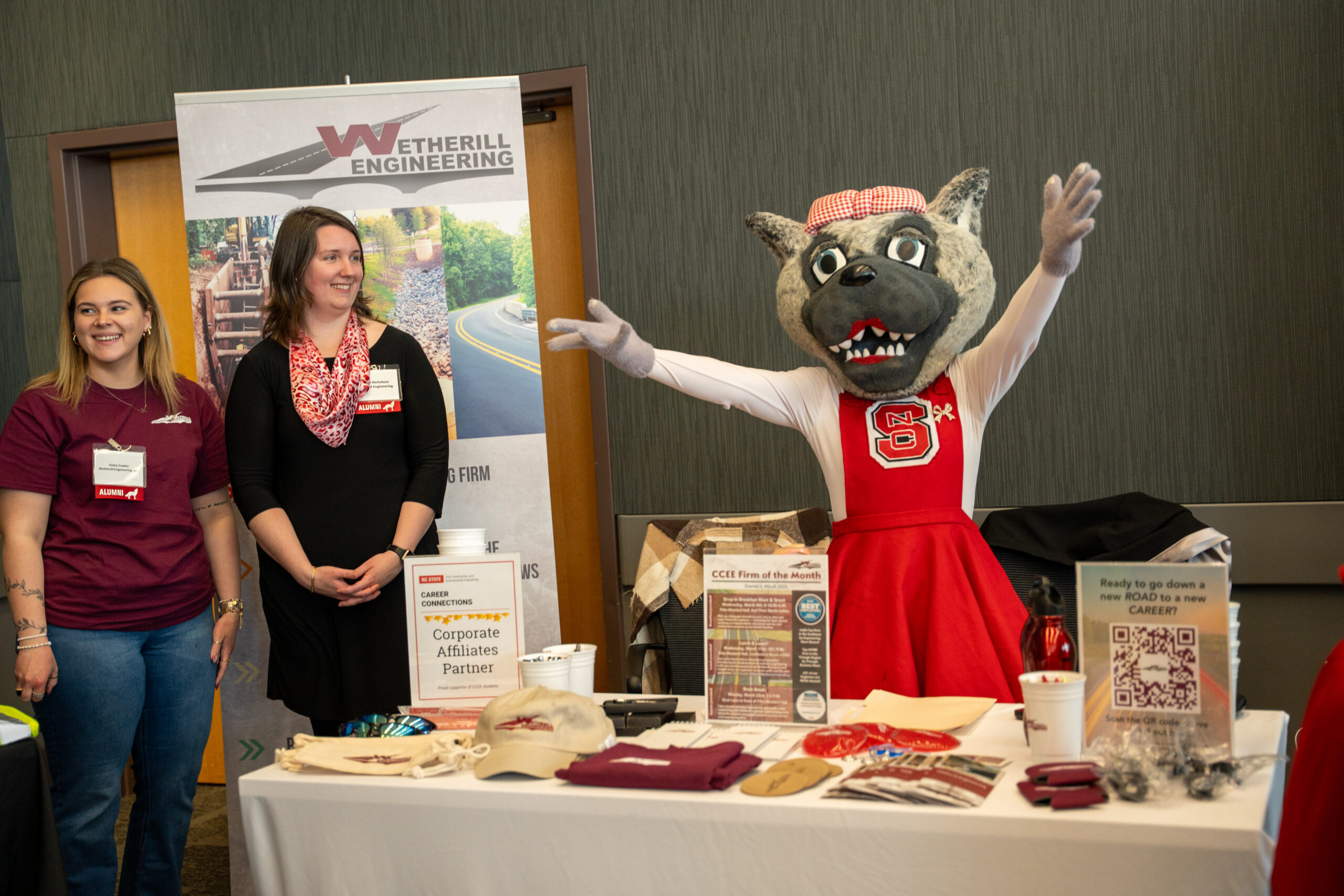 Image shows two women from Wetherill Engineering smiling next to Ms. Wuf at a career fair.