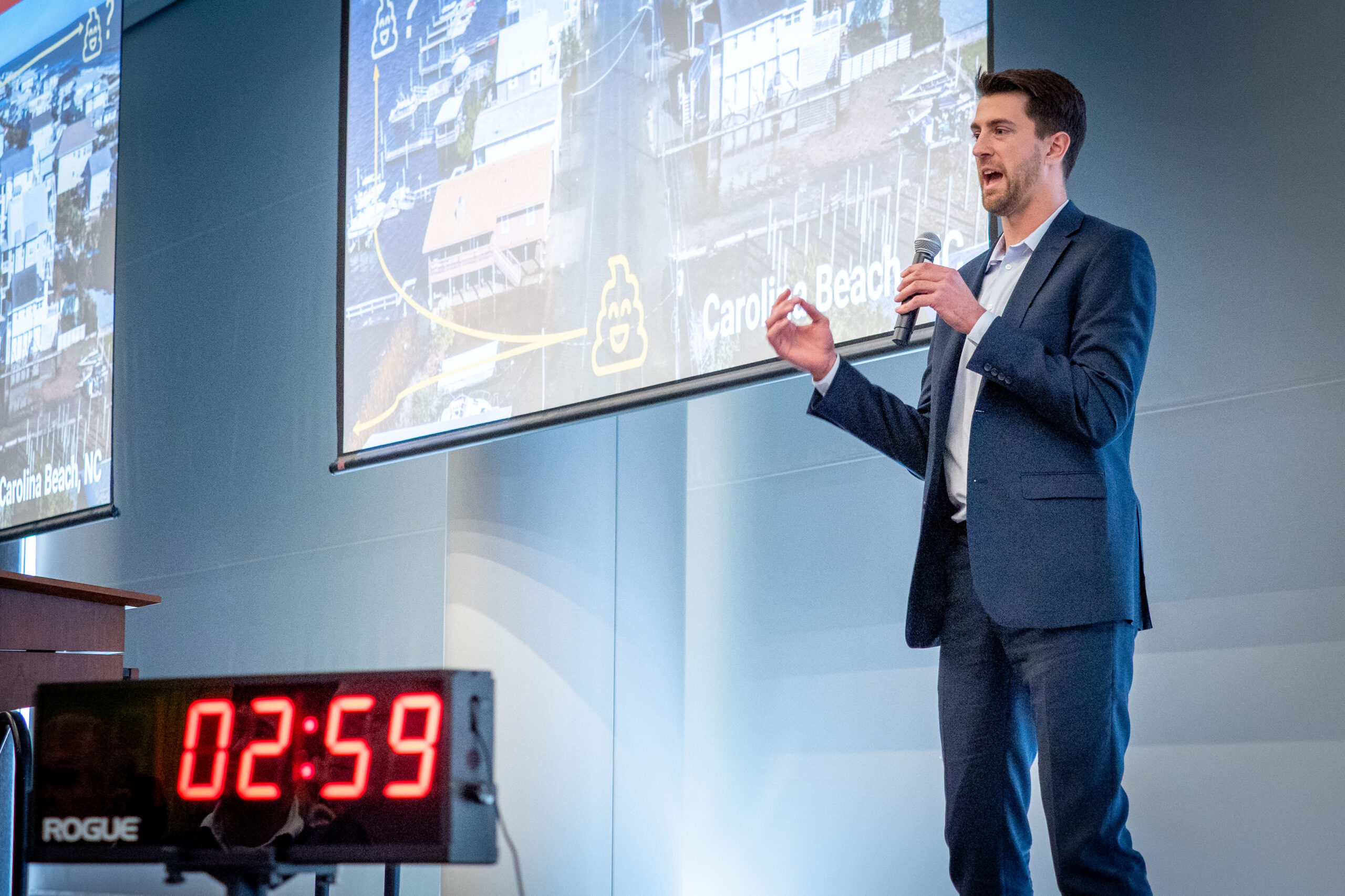 Image shows a graduate student explaining his research on a stage.
