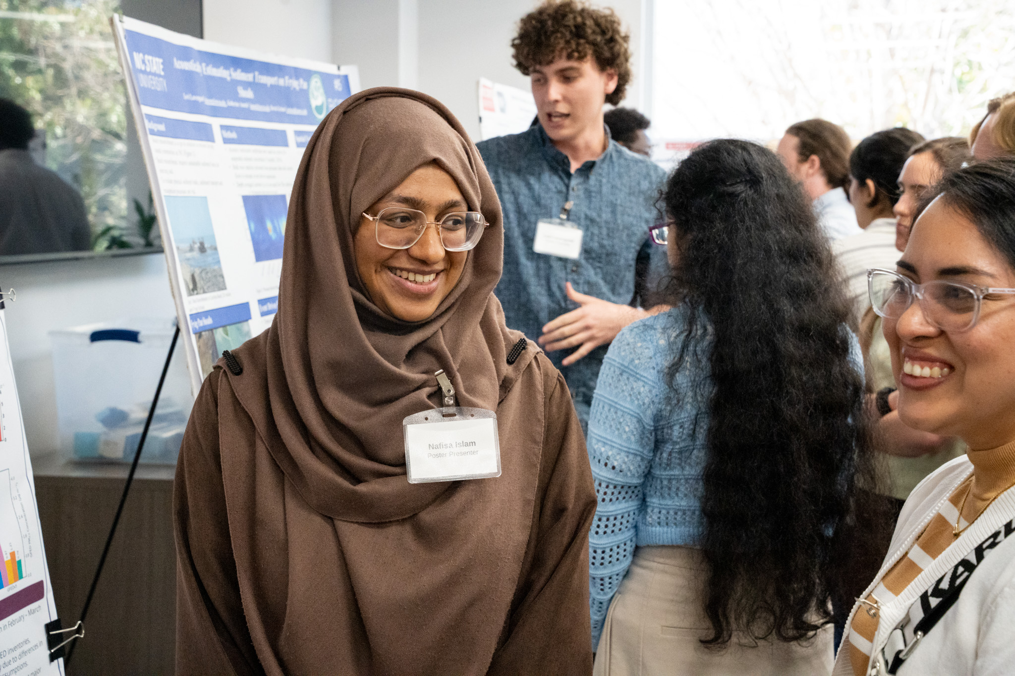 An NC State student smiling at another student at the EWC Symposium.
